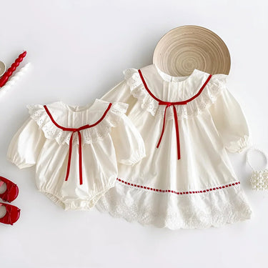 White baby dress with red trim and matching bloomers on a white background